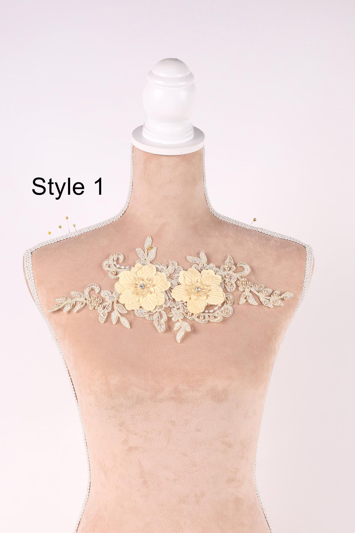 A mannequin with a decorative floral piece on its bust, featuring two yellow flowers and leaves.