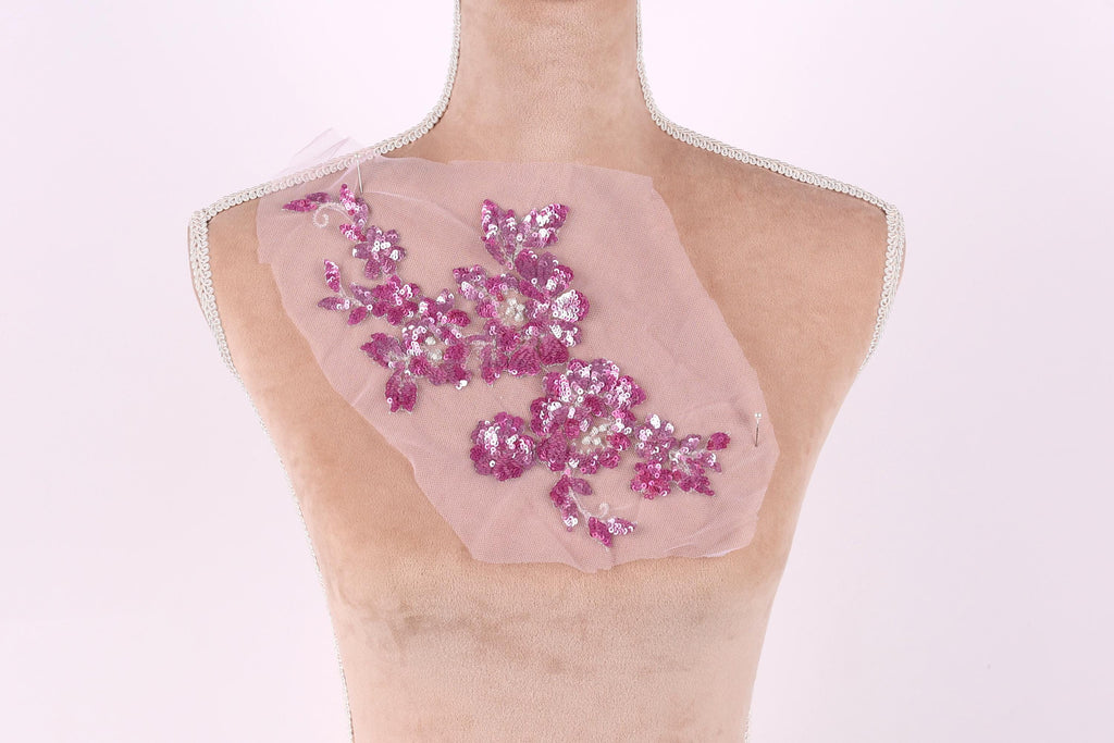 A mannequin with a pink fabric on its chest, featuring a floral pattern with pink and white sequins.