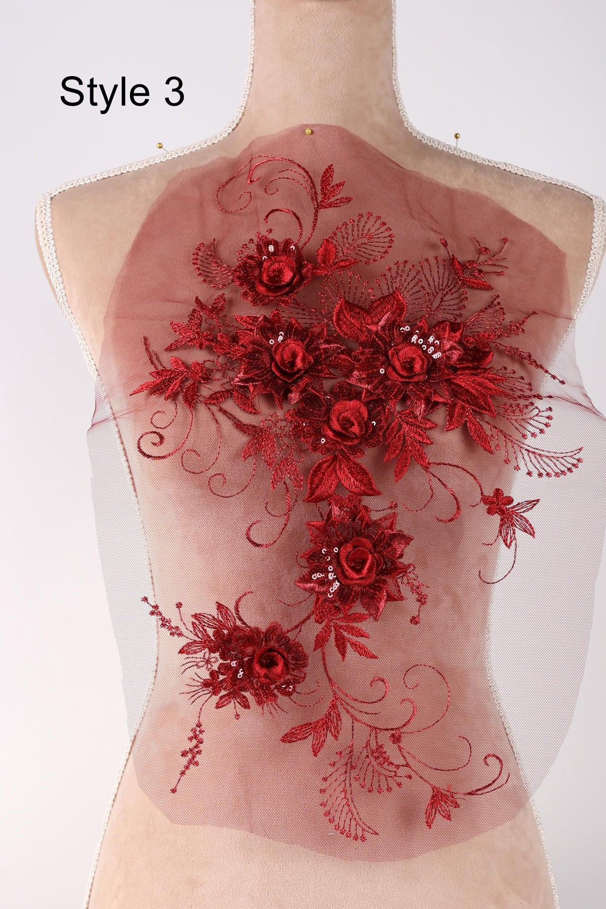 A mannequin with a red floral embroidered on its back.