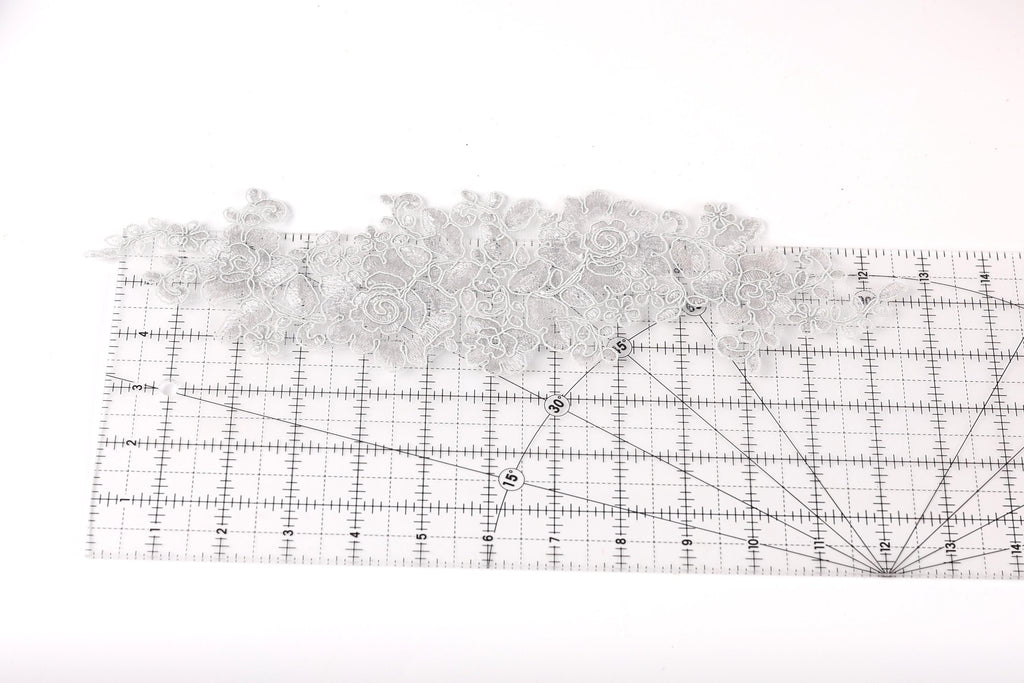 a piece of fabric with a floral pattern, placed on a ruler for size reference.