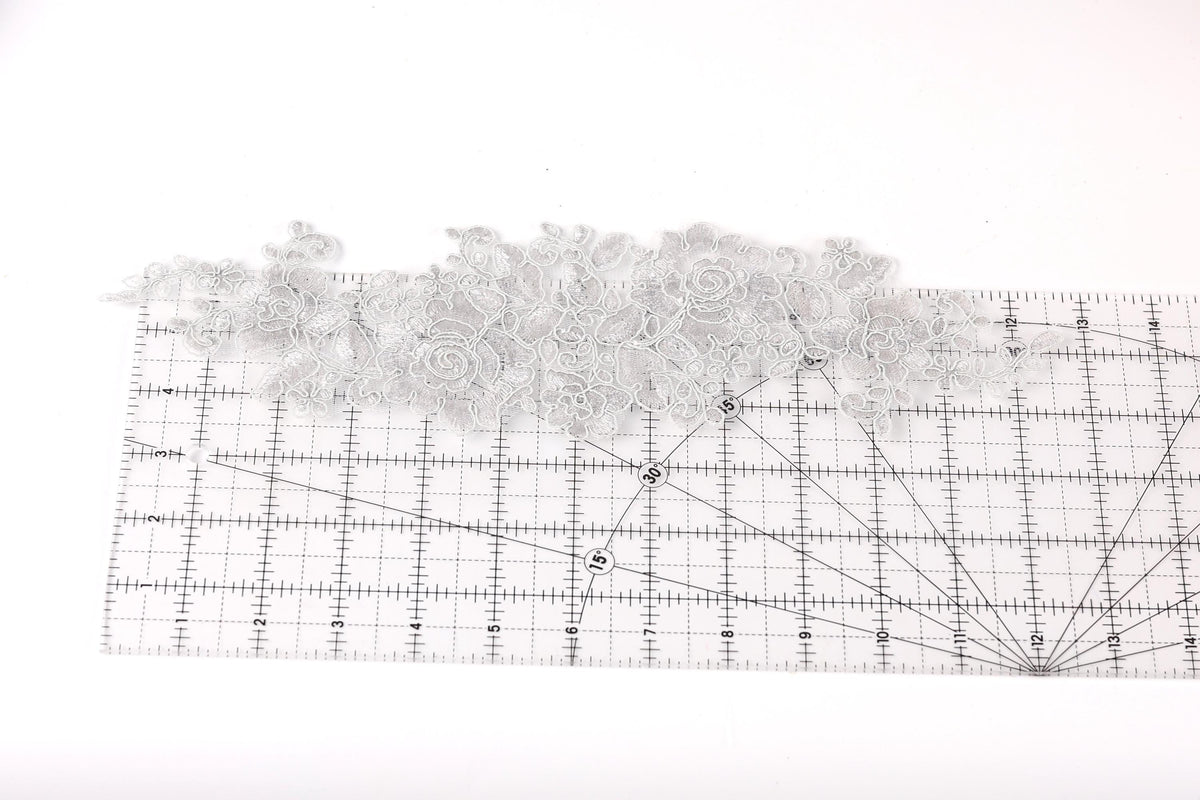 a piece of fabric with a floral pattern, placed on a ruler for size reference.