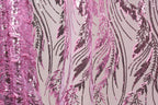 a close-up view of a fabric with a pink and black sequin pattern. The fabric appears to be a sheer material, with the pink sequins creating a visually striking contrast against the black background. The pattern consists of numerous sequins arranged in a repeating design, creating a sense of depth and texture. The image does not contain any discernible text or countable objects, and the focus is solely on the intricate and visually appealing pattern of the sequins.