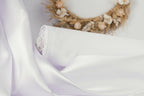 A white fabric roll with a floral wreath on a white background.