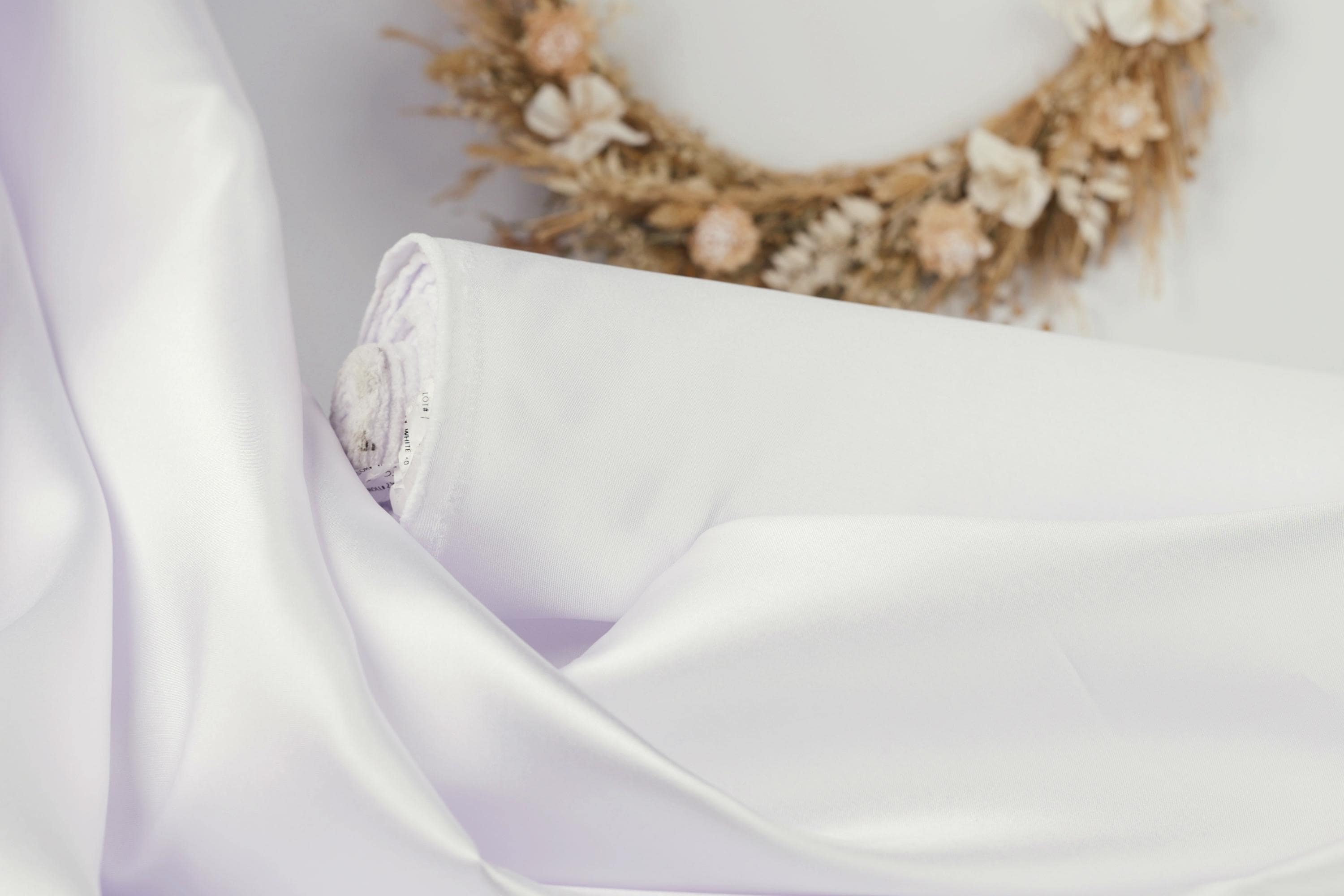 A white fabric roll with a floral wreath on a white background.