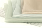 a close-up view of a stack of fabric swatches in various pastel colors, including light blue, light green, and beige.