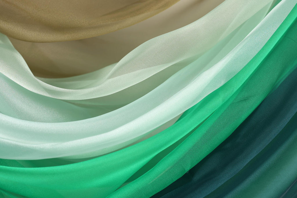 a close-up view of a variety of colorful fabric swatches, including shades of green, white, and brown.