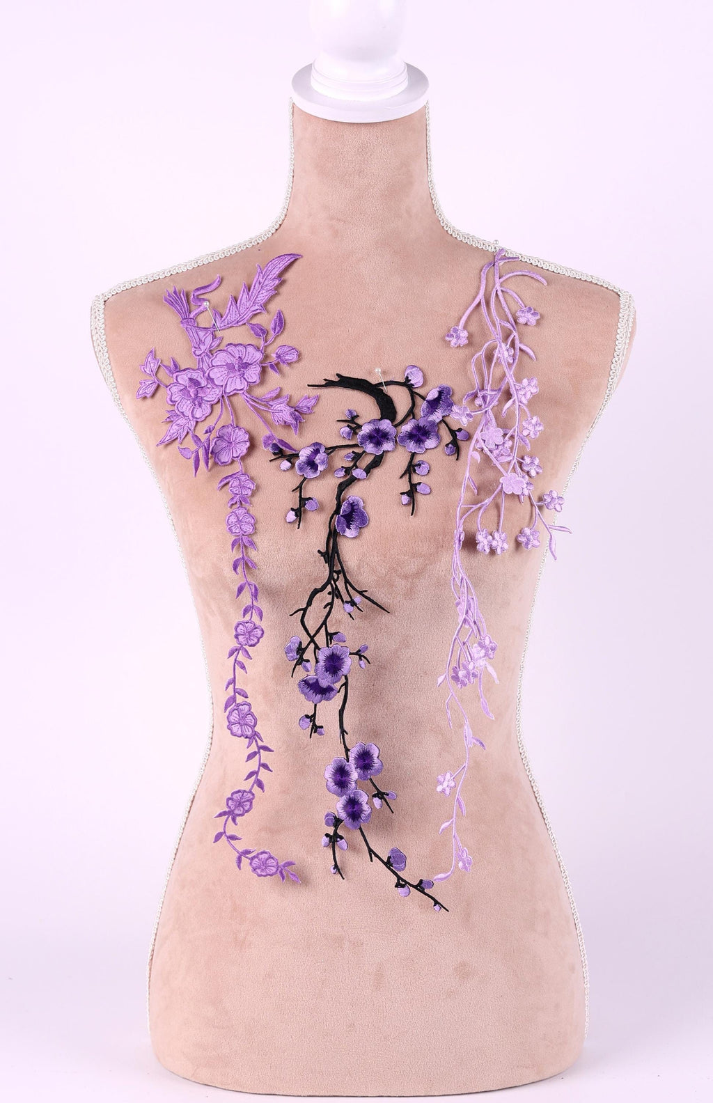 A mannequin torso with purple floral embroidery on it, including purple flowers and branches.