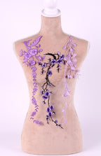 A mannequin torso with purple floral embroidery on it, including purple flowers and branches.