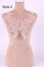 A mannequin wearing a pink lace neckline with delicate floral patterns.