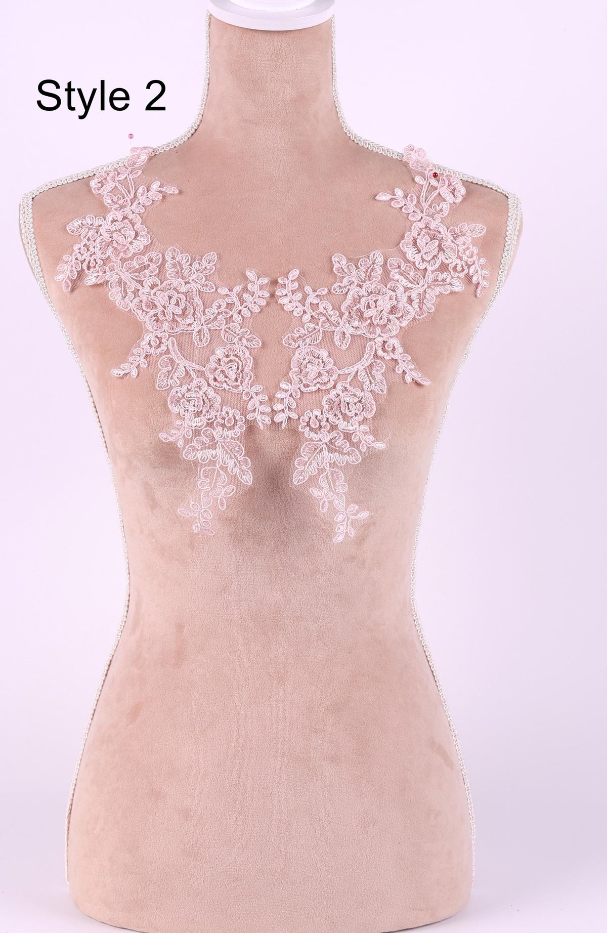 A mannequin wearing a pink lace neckline with delicate floral patterns.