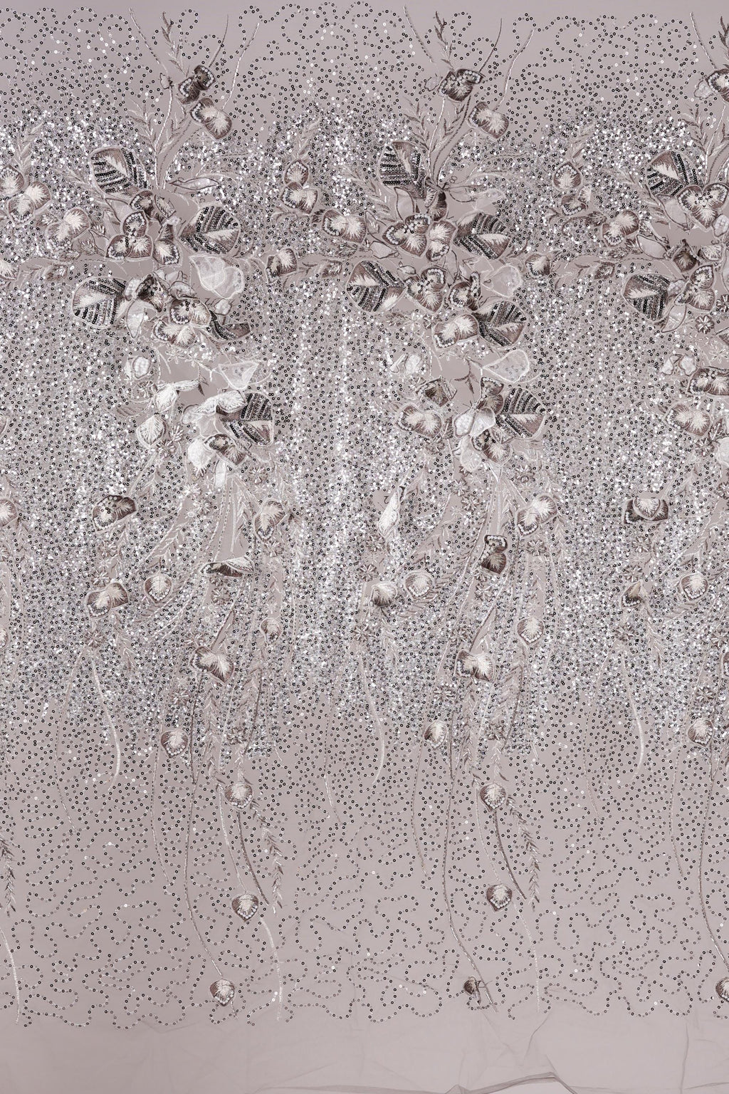 a close-up view of a fabric with a floral pattern, including small white flowers and leaves. The fabric appears to be made of a shiny, metallic material, giving it a metallic or metallic-like appearance. The pattern is intricate and detailed, with the flowers and leaves arranged in a repeating design across the fabric.