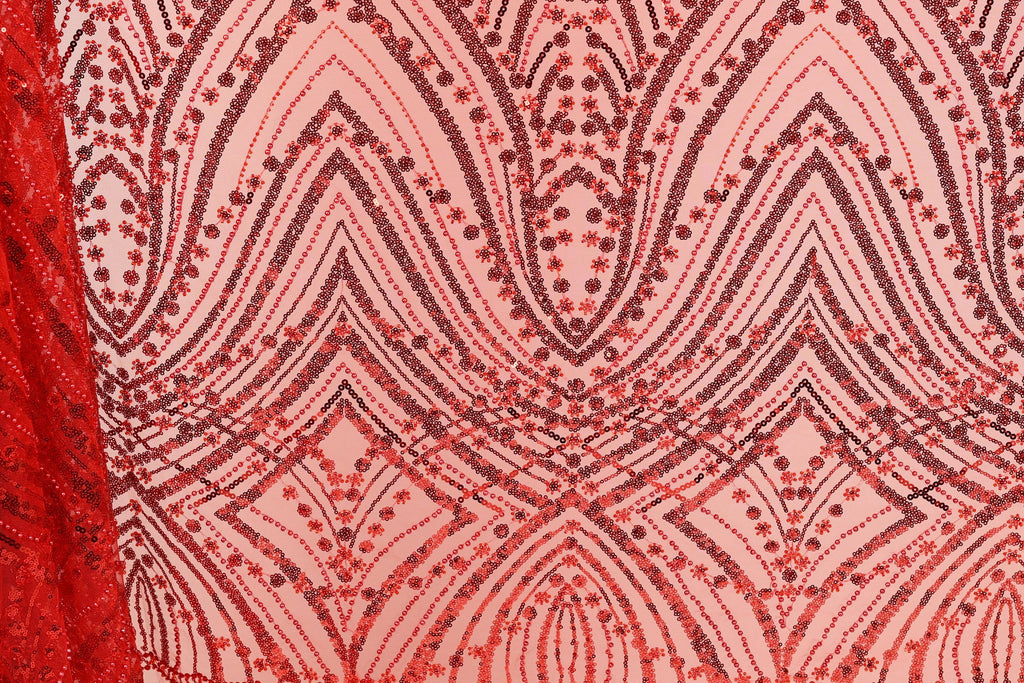 a close-up view of a fabric with a repeating pattern of red and black sequin designs. The pattern consists of various shapes and lines, creating a visually striking and intricate design. The fabric appears to be a piece of clothing or textile, with the red and black colors standing out prominently against the pink background.