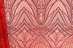 a close-up view of a fabric with a repeating pattern of red and black sequin designs. The pattern consists of various shapes and lines, creating a visually striking and intricate design. The fabric appears to be a piece of clothing or textile, with the red and black colors standing out prominently against the pink background.