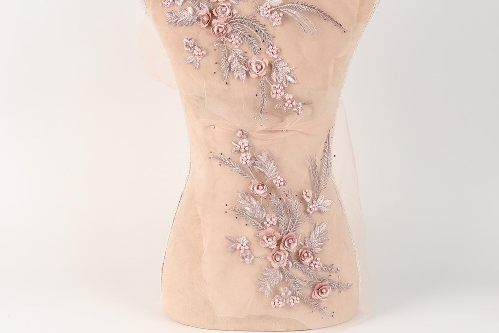 A mannequin with a delicate floral embroidered on its torso, featuring pink flowers and leaves.
