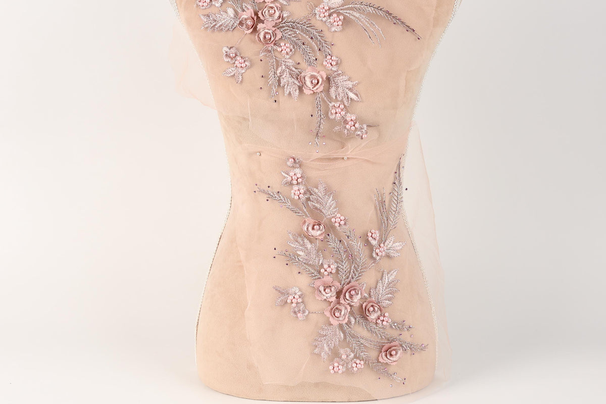 A mannequin with a delicate floral embroidered on its torso, featuring pink flowers and leaves.