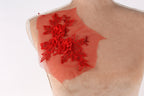 a close-up view of a mannequin torso with a red floral embroidered on the shoulder.