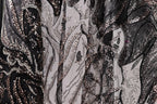 The image is a close-up of a fabric with a black and white pattern, featuring a mix of glittering and metallic elements.