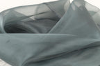 a close-up view of a piece of gray fabric, possibly silk or chiffon, with a slightly wrinkled texture.