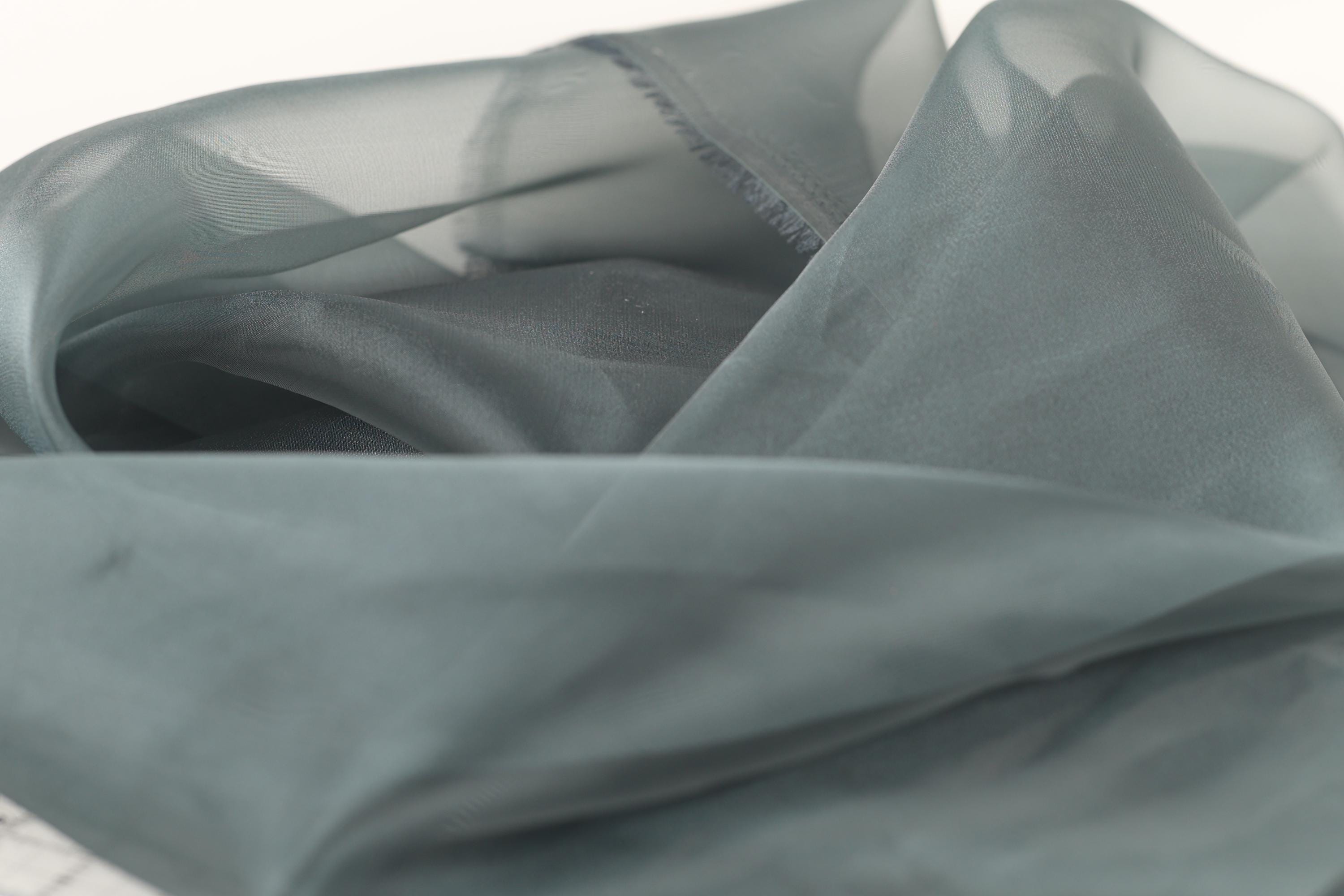 a close-up view of a piece of gray fabric, possibly silk or chiffon, with a slightly wrinkled texture.