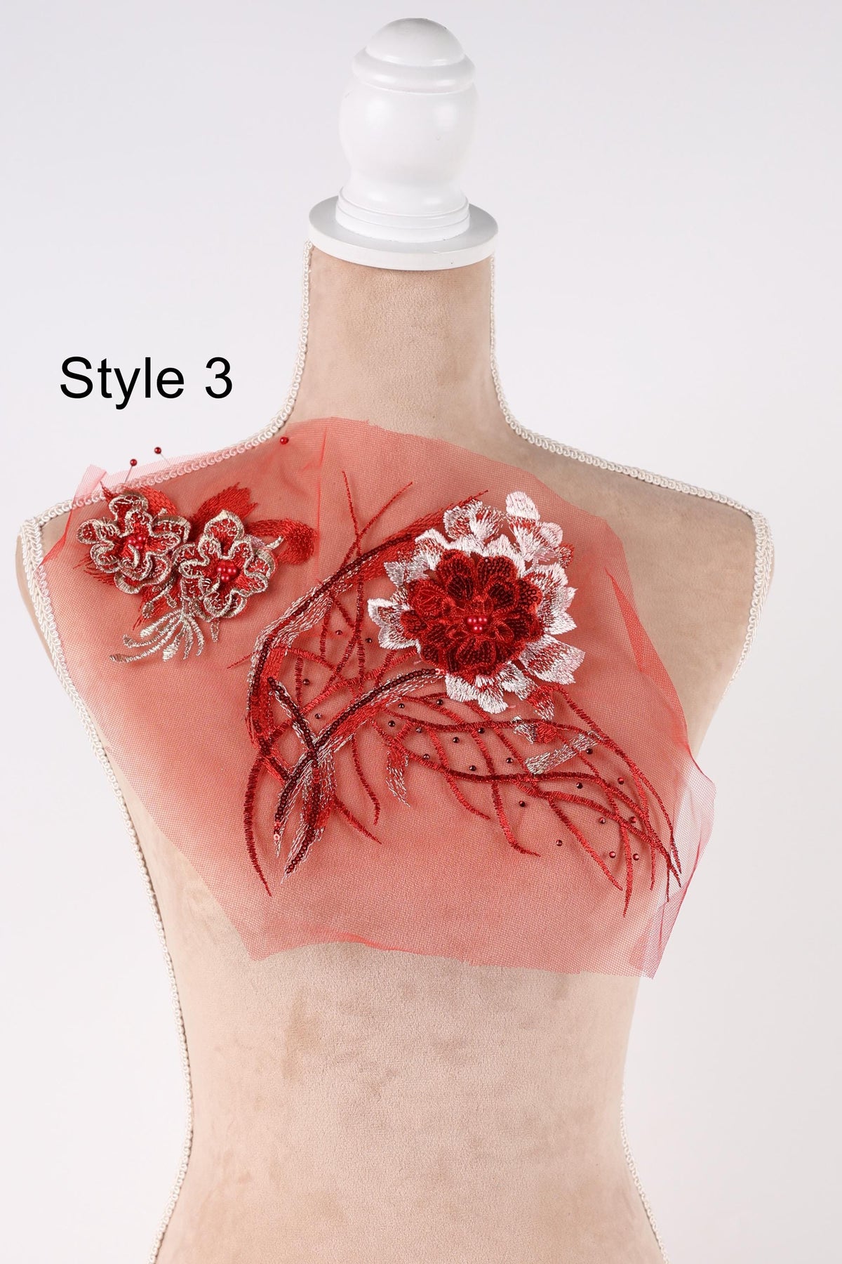 A mannequin wearing a red and white floral embroidered piece of fabric, with the text "Style 3" indicating the style of the piece.