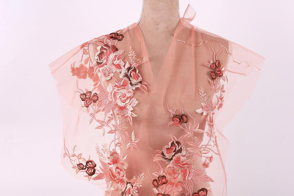 A mannequin wearing a pink dress with intricate floral embroidery.