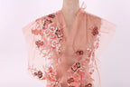 A mannequin wearing a pink dress with intricate floral embroidery.