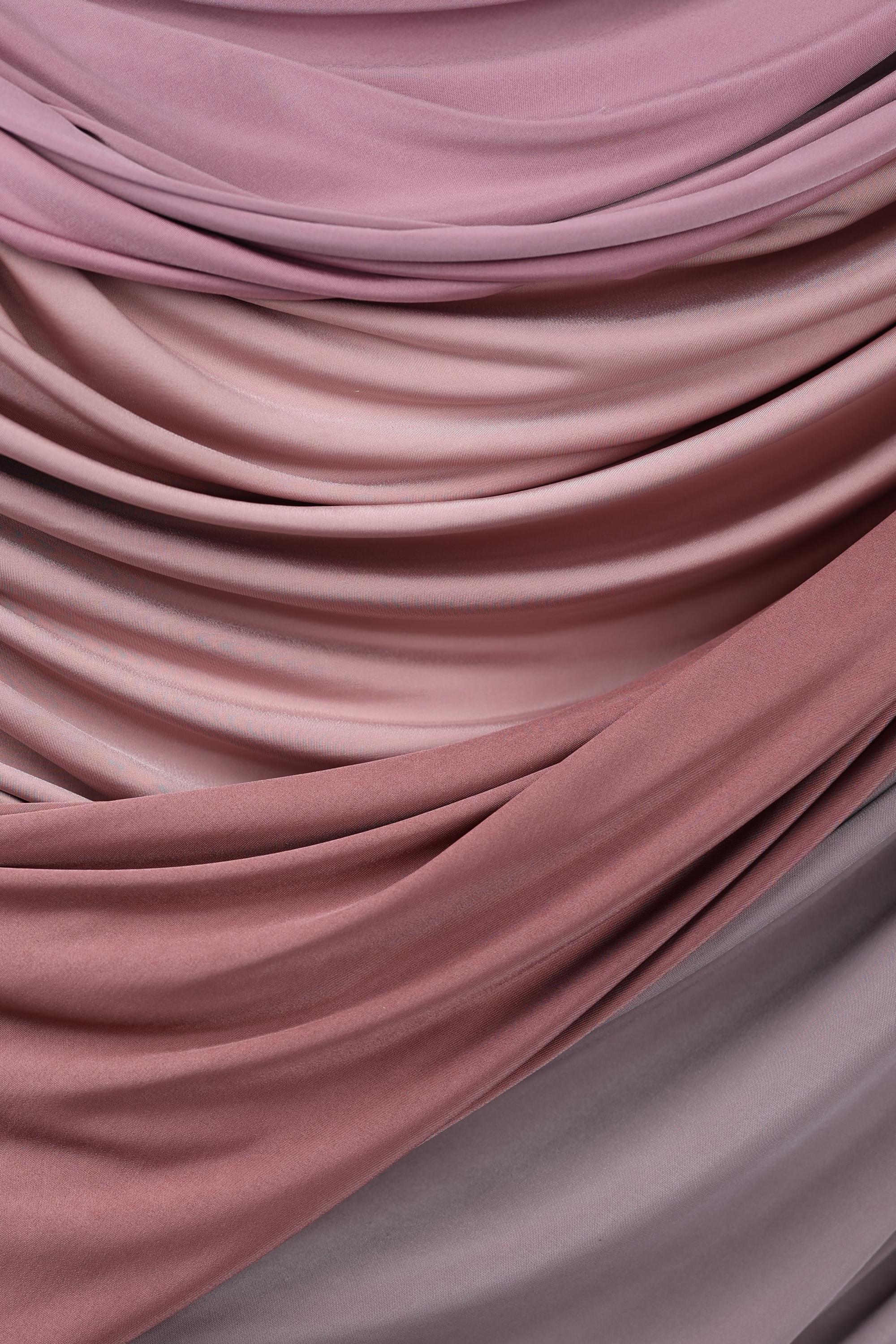 a close-up view of a fabric with a soft, flowing texture in shades of pink and purple. The fabric appears to be made of a soft, plush material, possibly cotton or silk, and is arranged in a way that creates a sense of movement and depth. The colors and texture of the fabric create a visually appealing and harmonious composition.