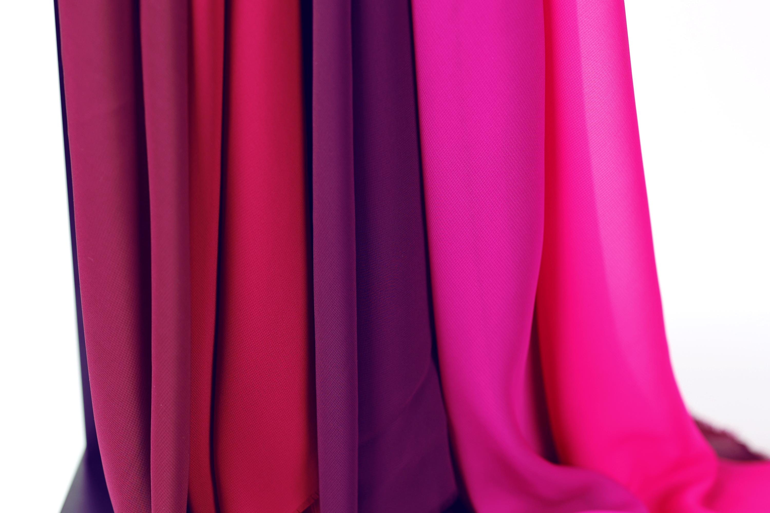 a close-up view of a collection of colorful fabric swatches, including red, purple, and pink hues.