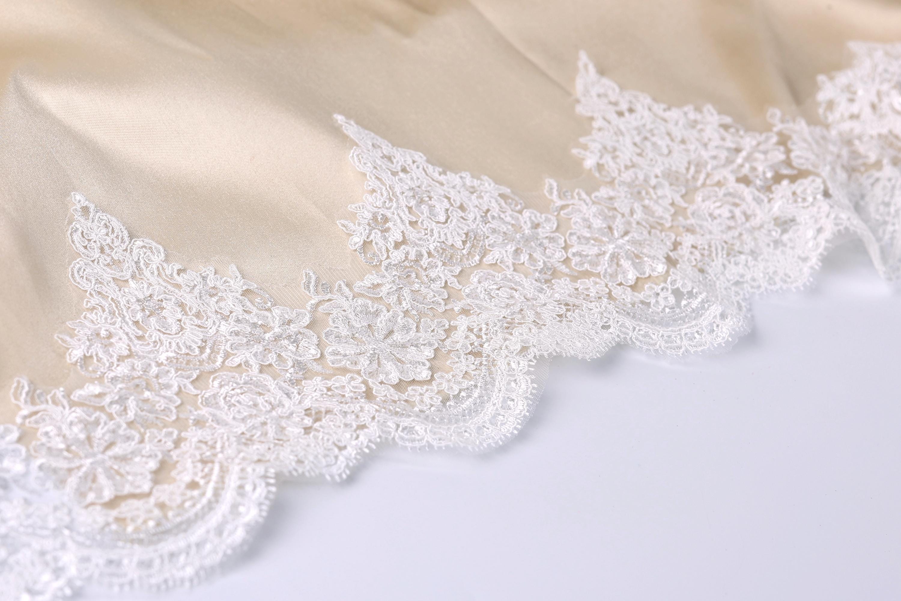 A close-up view of a delicate, white lace trim on a fabric surface.