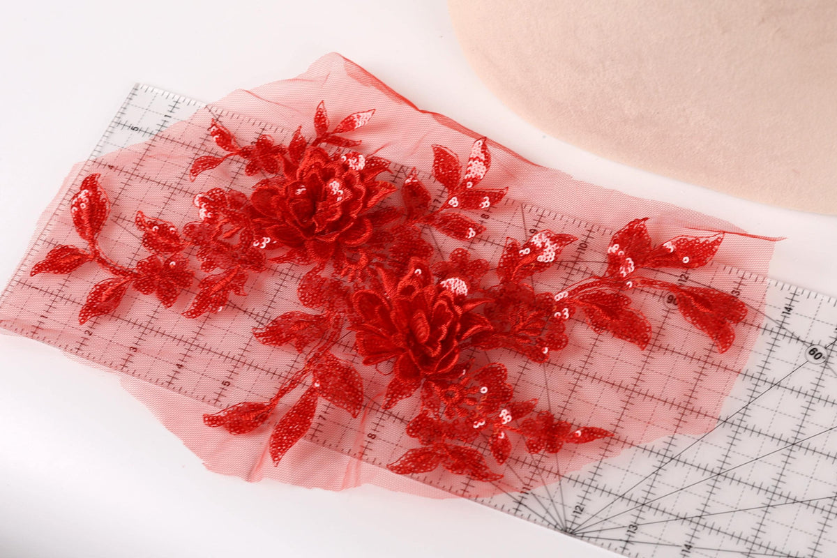 a red floral embroidery with sequins, placed on a transparent surface.
