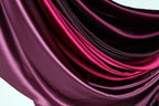 a close-up view of a fabric with a gradient of colors, transitioning from a deep purple to a lighter shade of purple. The fabric appears to be made of satin or a similar smooth, shiny material.