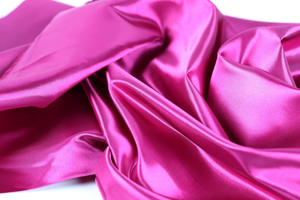 The image is a close-up of a shiny, smooth, and vibrant pink satin fabric.