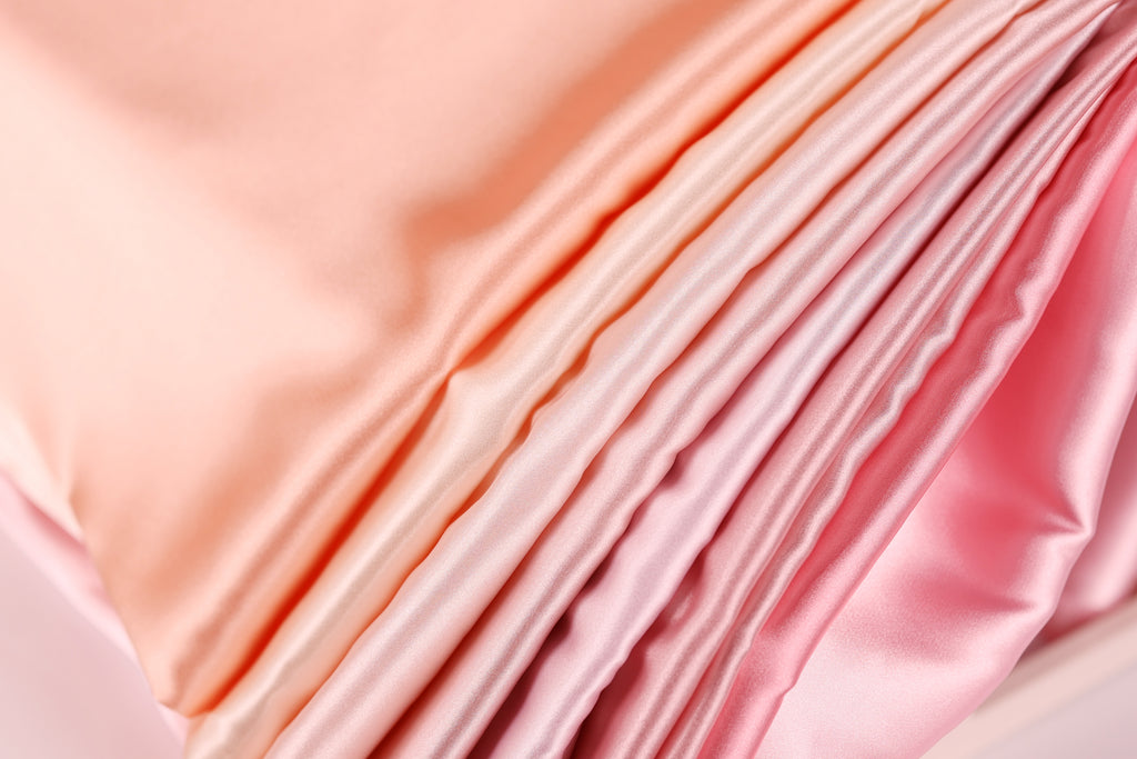 A close-up view of a soft, flowing fabric with a gradient of pink and peach colors, creating a visually appealing and textured appearance.