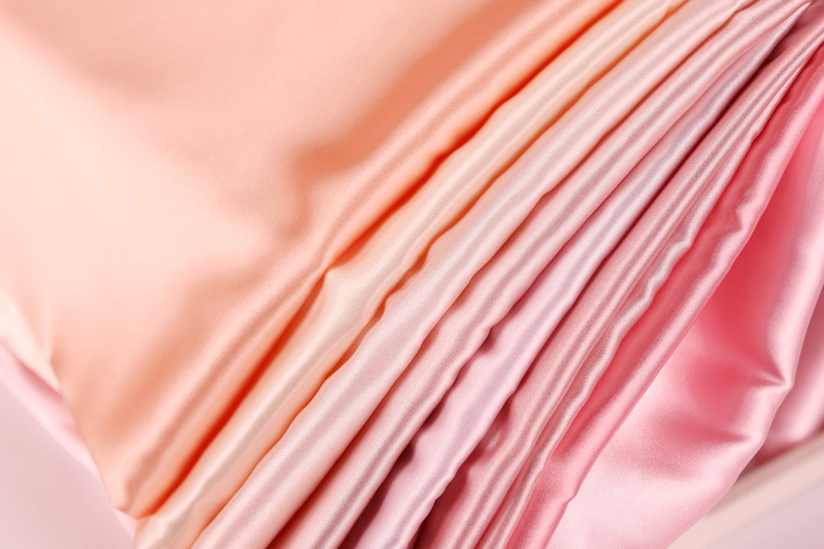A close-up view of a soft, flowing fabric with a gradient of pink and peach colors, creating a visually appealing and textured appearance.