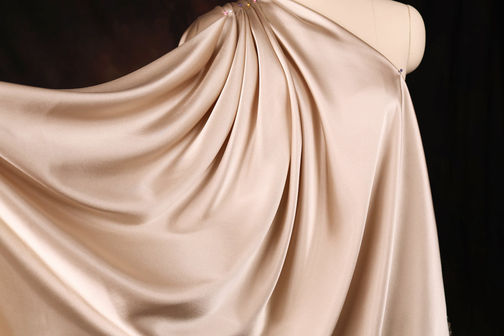 A close-up view of a flowing, draped fabric in a light beige color.