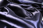 a close-up view of a shiny, dark blue satin fabric, with a slightly crumpled texture.