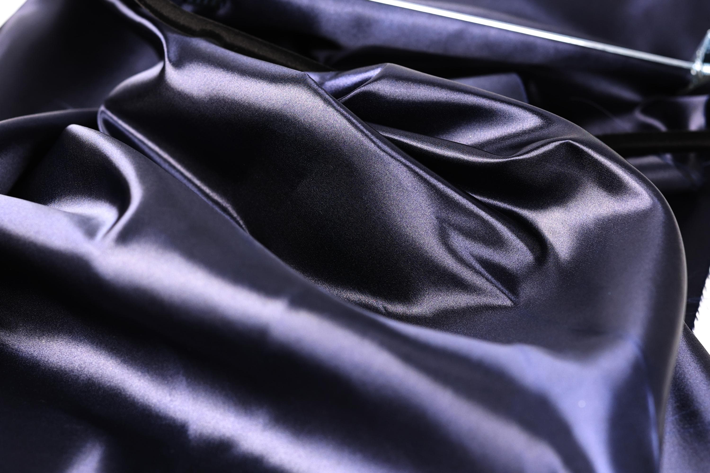 a close-up view of a shiny, dark blue satin fabric, with a slightly crumpled texture.