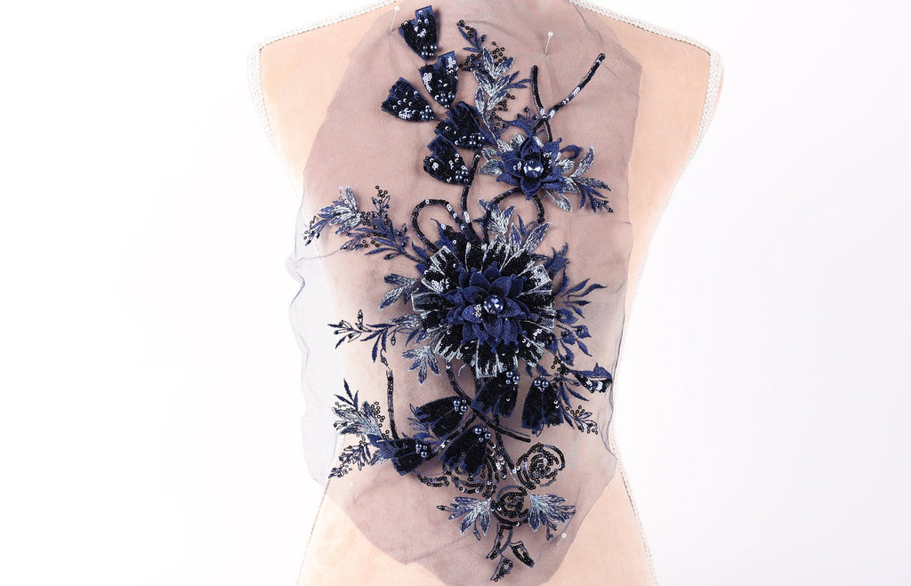 a mannequin with a decorative back piece that has a floral design. The back piece is made of a sheer fabric with a blue and black floral pattern, and it appears to be attached to the mannequin's back.