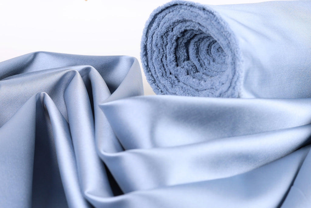 a close-up view of a blue fabric, possibly silk or satin, with a rolled-up end visible.