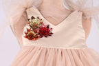 A close-up view of a beige dress with a floral design on the front.