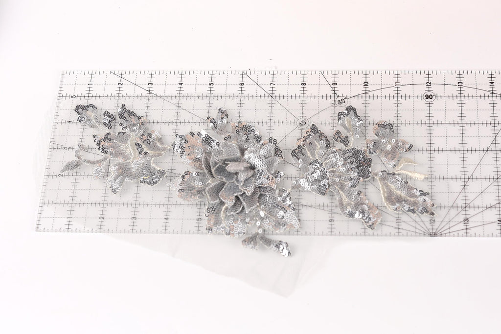 a clear ruler with a silver sequin flower design placed on it.