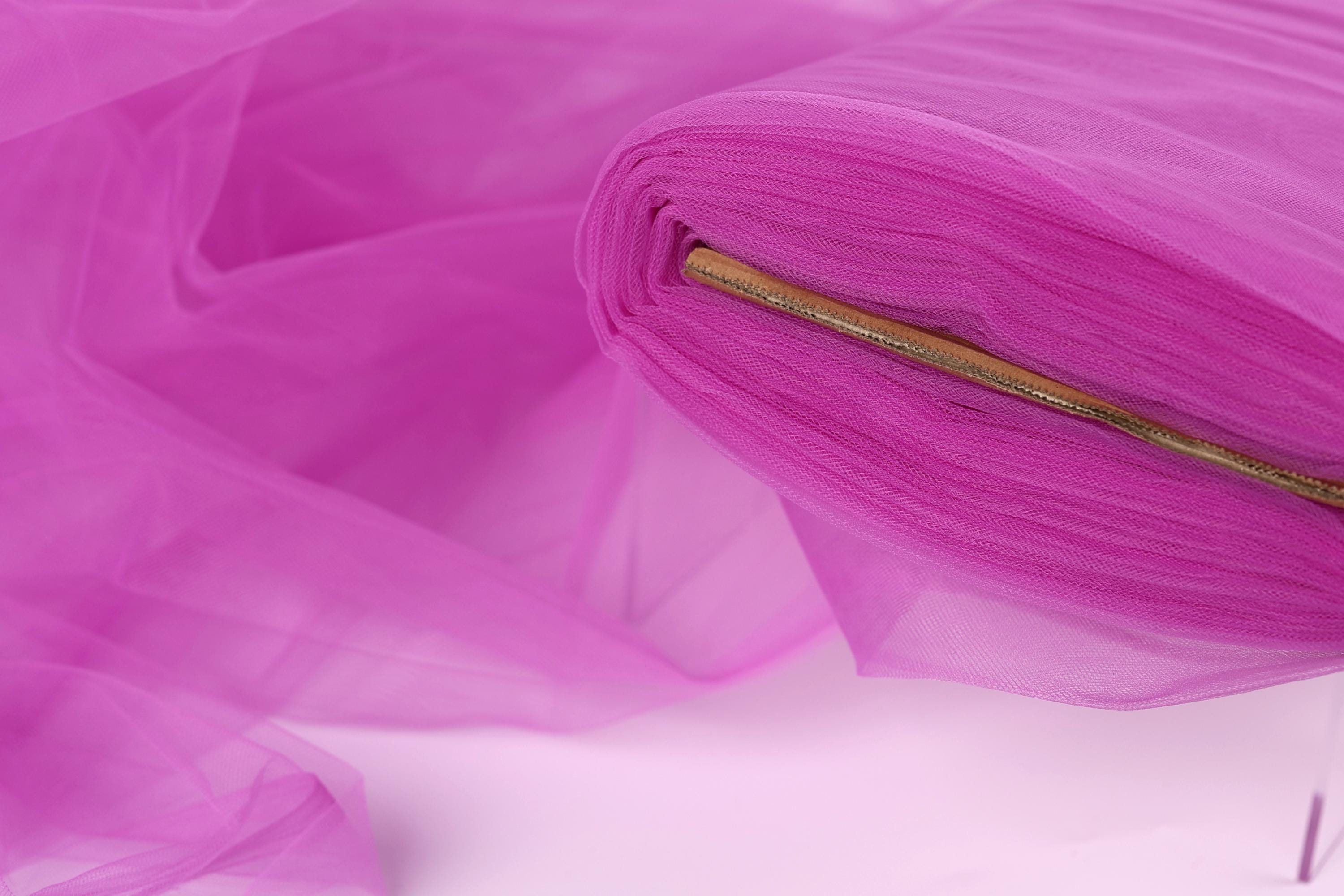 A close-up view of a piece of pink tulle fabric, with a zipper visible on the right side.