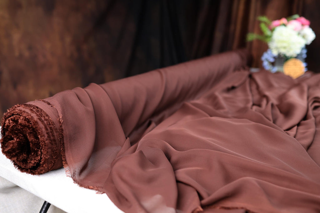 a bed with a brown comforter and a vase of flowers