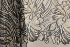 a close-up view of a fabric with a floral pattern, showcasing intricate details and a blend of black and gold colors.