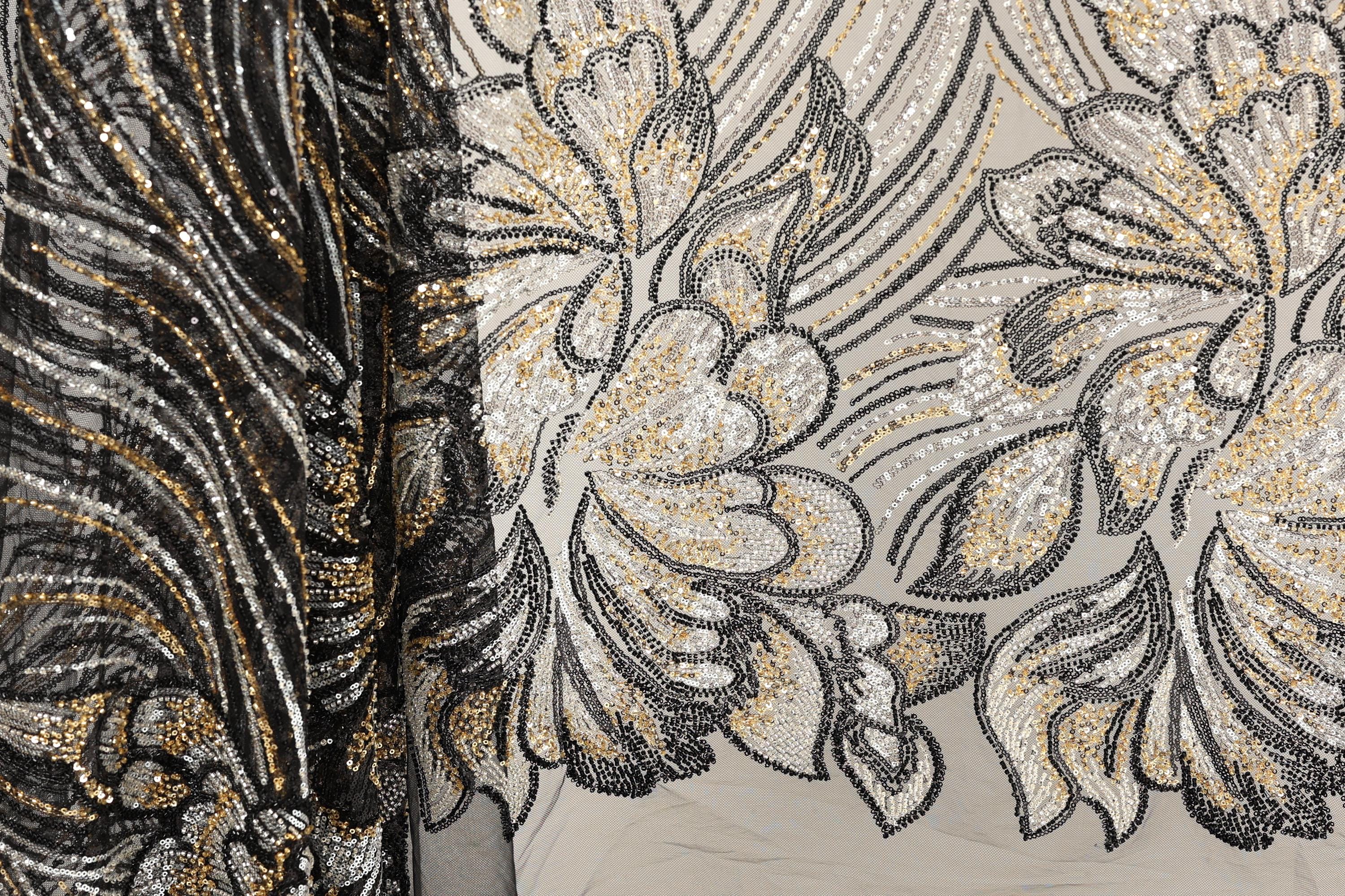 a close-up view of a fabric with a floral pattern, showcasing intricate details and a blend of black and gold colors.