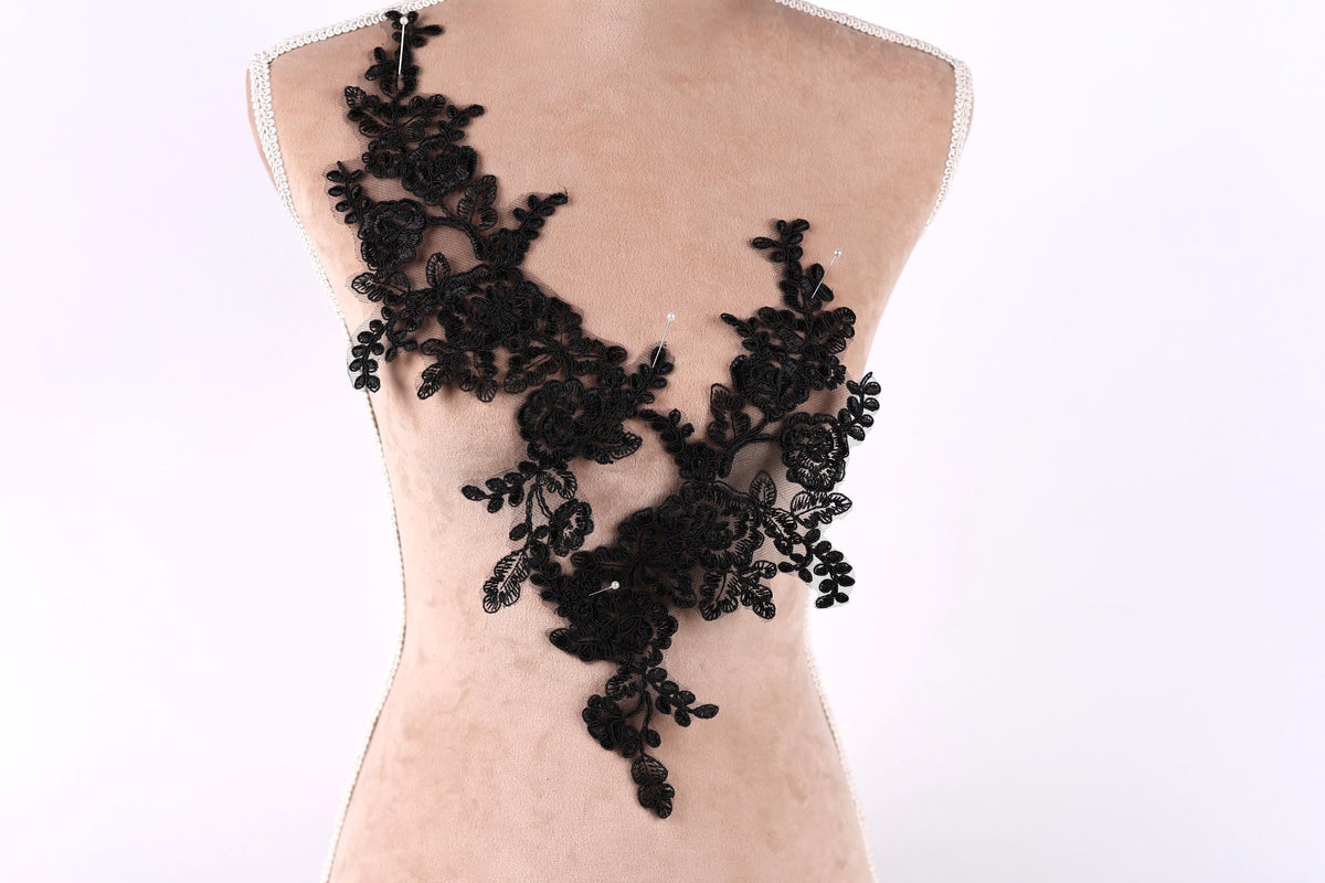 A mannequin torso with a black lace overlay, featuring intricate floral and leaf designs.
