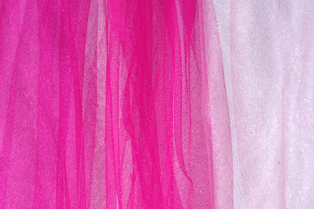 The image is a close-up of a fabric with a pink and white color scheme. The fabric appears to be a sheer material, with a pink hue dominating the background and a white hue in the foreground. The fabric has a textured appearance, with vertical lines and a slightly wrinkled texture.