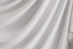 The image is a close-up of a white fabric, possibly a sheer or sheer-like material, with a soft, flowing texture.