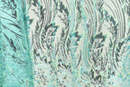 a close-up view of a fabric with a repeating pattern of green and black lines and shapes, creating a visually striking and intricate design.