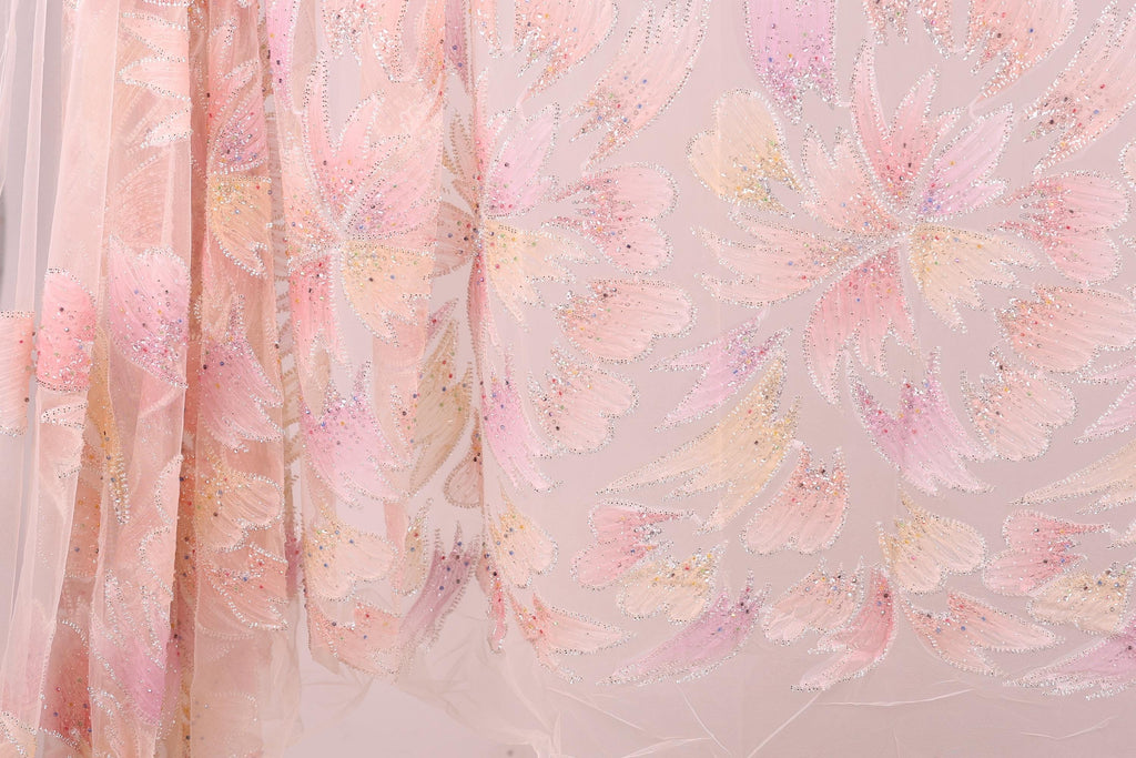 a close-up view of a delicate, pastel-colored fabric with a floral pattern. The fabric appears to be made of sheer material, giving it a soft and delicate appearance. The floral pattern consists of various shades of pink and yellow, creating a visually appealing and intricate design. The fabric is spread out, allowing for a clear and detailed view of its texture and pattern.